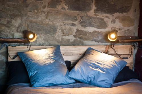 a bed with blue pillows and two lights on it at Can Poca Roba in Sant Pere de Torelló