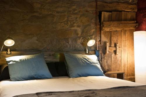una camera da letto con un letto con due cuscini e due luci di Can Poca Roba a Sant Pere de Torelló