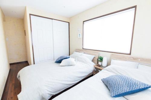 two beds in a room with a large window at パームヴィラ-貸切プライベート-最大10名様のバケーションステイ-駐車場付き in Yaese