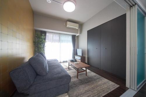 a living room with a couch and a table at nedoco OSAKA SHINSAIBASHI - formerly FORESTAY Shinsaibashi in Osaka