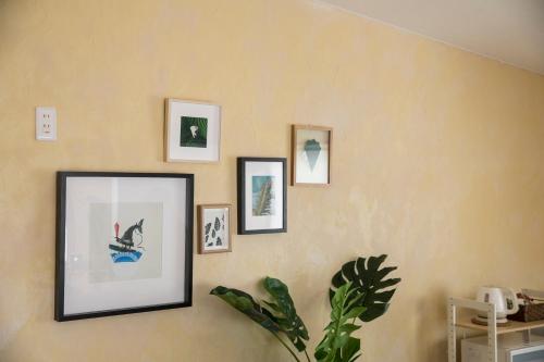 a wall with pictures and a plant on it at パームヴィラ-貸切プライベート-最大10名様のバケーションステイ-駐車場付き in Yaese