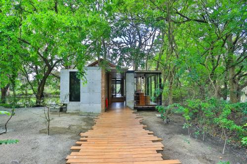 a small house with a wooden walkway leading to it at Kalundewa Retreat in Dambulla