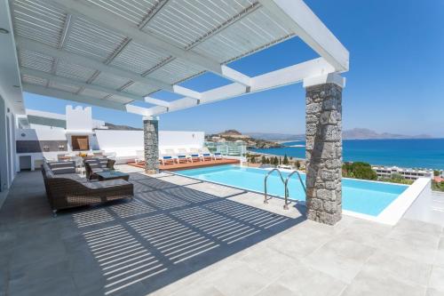 a villa with a swimming pool and the ocean at Luxury Sunrise White Villa in Lindos
