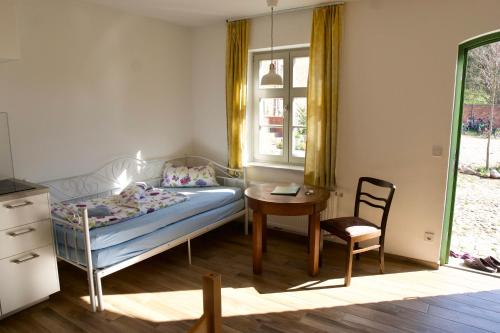 a bedroom with a bed and a table and a chair at Mirabellenhof- Remise in Biesenthal
