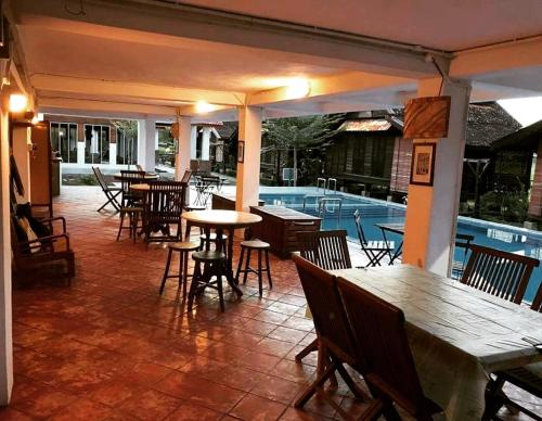 a patio with tables and chairs and a swimming pool at tanabendang banglos in Pantai Cenang
