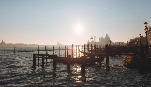 a dock in the water with the sun setting at Venice Maggior Consiglio in Venice