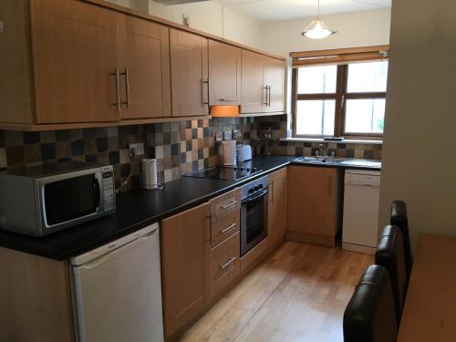 a large kitchen with wooden cabinets and a microwave at 4 Clifden Court in Clifden