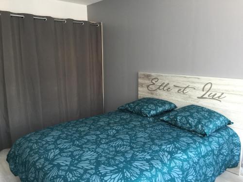 - un lit avec une couette bleue et 2 oreillers dans l'établissement Entre mer et falaises, au Tréport