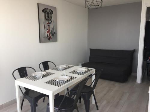 une table blanche avec des chaises et un canapé noir dans l'établissement Entre mer et falaises, au Tréport