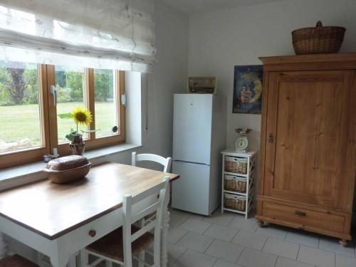 eine Küche mit einem Tisch, einem Kühlschrank und einem Fenster in der Unterkunft Ferienwohnung Fantaisie in Eckersdorf