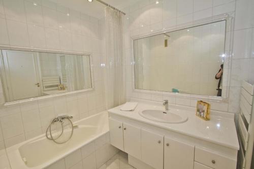 La salle de bains blanche est pourvue d'un lavabo, d'une baignoire et d'un miroir. dans l'établissement PROMENADE HOLIDAY - CARIATIDE PROMENADE SEA VIEW, à Nice