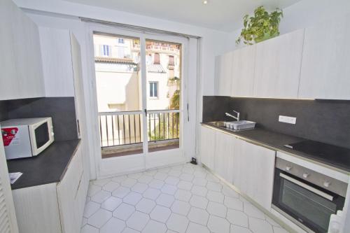 une cuisine avec évier et four micro-ondes ainsi qu'une fenêtre dans l'établissement PROMENADE HOLIDAY - CARIATIDE PROMENADE SEA VIEW, à Nice