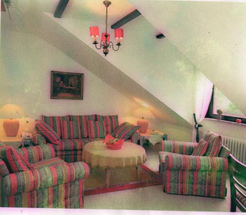 a living room with couches and a table and a chandelier at Wellness und Romantik Hotel Helmboldt in Bad Sachsa