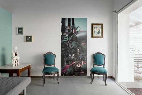 two chairs in a living room with a painting on the wall at Naturarte Guesthouse in Terrasini