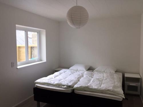 a bedroom with a bed with white sheets and a window at Private Spacious Home in City Center in Klaksvík
