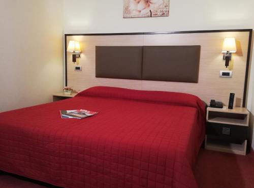 a red bed in a hotel room with a red bedspread at Hotel Des Alpes in Castione della Presolana