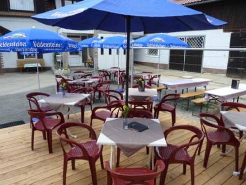 a group of tables and chairs with blue umbrellas at Cafe und Pension Ringer in Vilseck