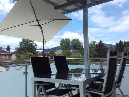 a table and chairs with an umbrella on a balcony at Apartment and more in Klagenfurt