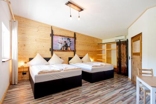 two beds in a room with wooden walls at Zündstoff-City Western-Motel in Hemfurth-Edersee