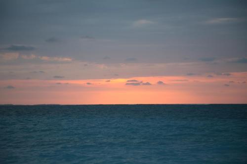 a sunset over the ocean with the horizon at The Atrium Resort in Grace Bay