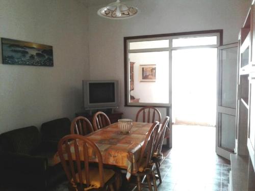 uma sala de jantar com uma mesa e cadeiras e uma televisão em Mare&Monti II em Telti