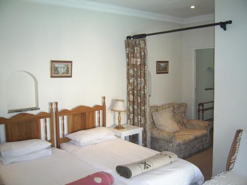 a bedroom with two beds and a chair and a mirror at Nutmeg Guest House in Howick