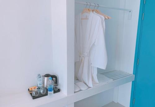 a closet with white clothes and shoes on a shelf at Blue Tao Beach Hotel - SHA Plus in Koh Tao