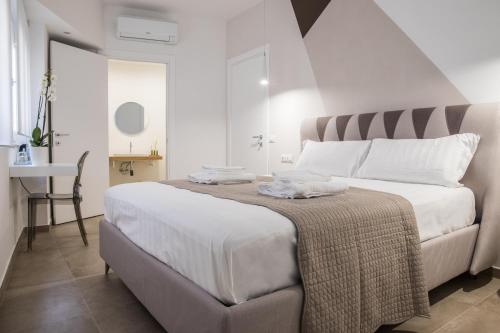 Biała sypialnia z dużym łóżkiem i biurkiem w obiekcie SuitesGaribaldi w Cagliari