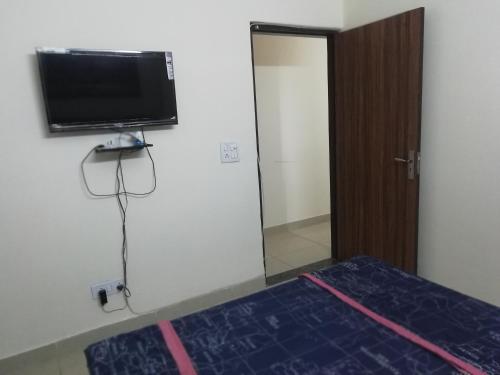 a bedroom with a tv and a bed and a mirror at The Raveesh E24 - 2BHK Serviced Apartment in New Delhi