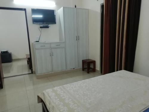 a bedroom with a bed and a cabinet and a television at The Raveesh E24 - 2BHK Serviced Apartment in New Delhi