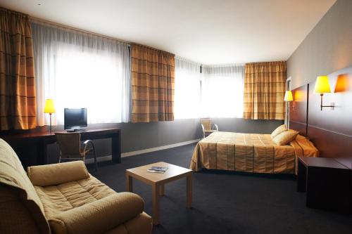una habitación de hotel con una cama y un sofá en Hotel De Loire et Restaurant Les Bateliers, en Trélazé