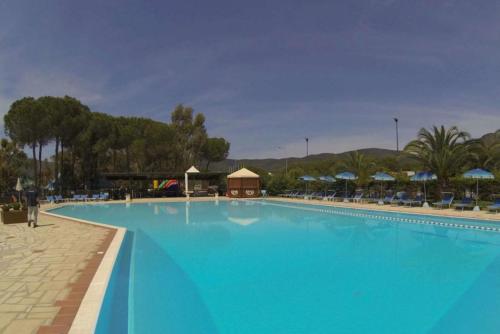 a large blue swimming pool with a building in the background at Elba Travels - Lacona in Lacona