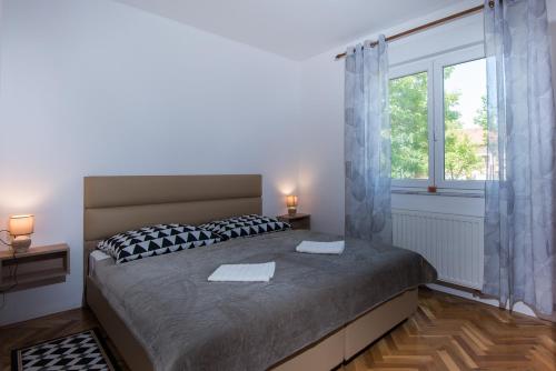 a bedroom with a large bed and a window at Seasons apartmani in Osijek