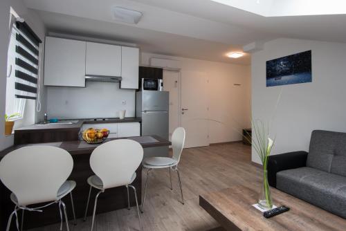 a kitchen and living room with a table and chairs at Seasons apartmani in Osijek