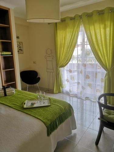 a bedroom with a bed with a green blanket and a window at Casa Dos Cedros in Lagos