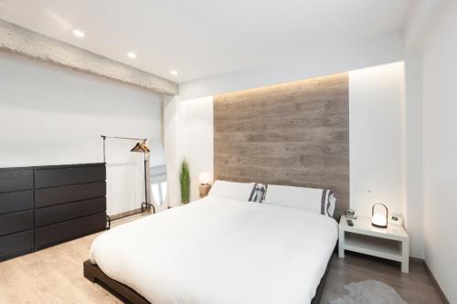 1 dormitorio con cama blanca y pared de madera en Apartamento Egia, en San Sebastián