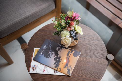 a table with a vase of flowers and a book at U Chiangkhan in Chiang Khan