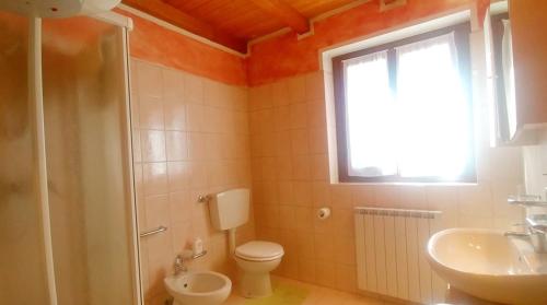 a bathroom with a toilet and a sink and a window at Casa Beatrice in Aprica