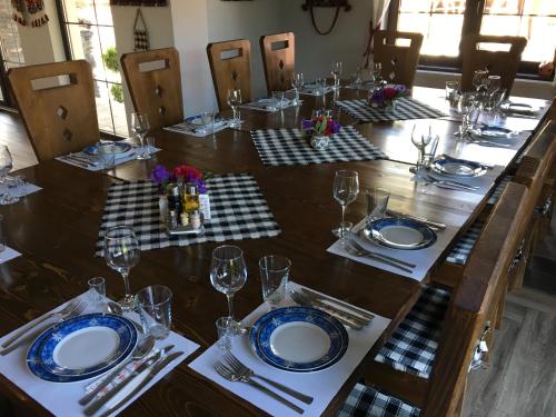 a long wooden table with plates and wine glasses at La Conacul Vesel Săpânța in Săpînţa
