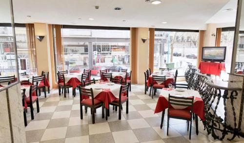 a dining room with tables and red chairs and windows at Vernisa in Xàtiva