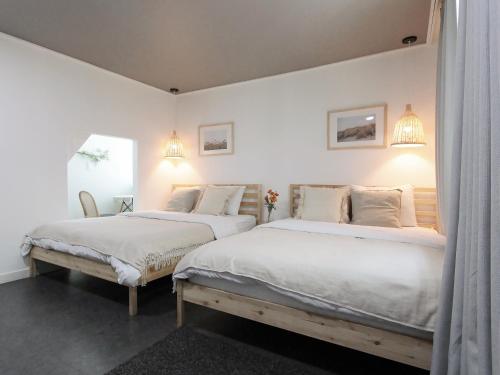 two beds in a bedroom with white walls at Neat House in Seoul