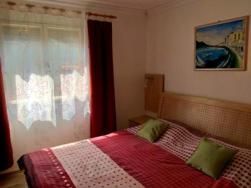 a bedroom with a bed with a red blanket and a window at Popeye Vendégház Zsóryfürdő in Mezőkövesd