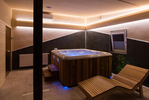 a large bathroom with a hot tub and a bench at Seasons apartmani in Osijek