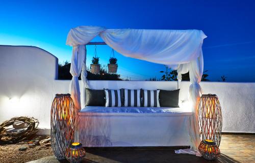 a white bed with a canopy on a patio at Golden East in Imerovigli