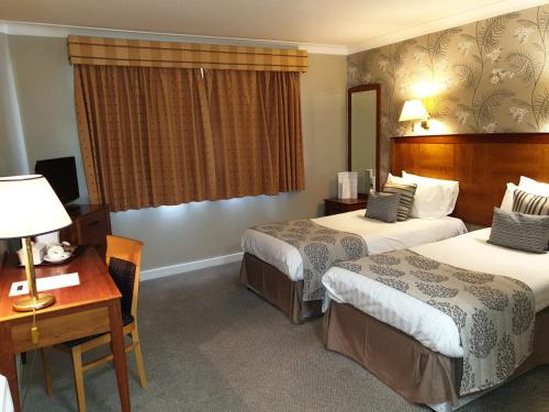 ベージングストークにあるレッド ライオン ホテルのベッド2台とデスクが備わるホテルルームです。
