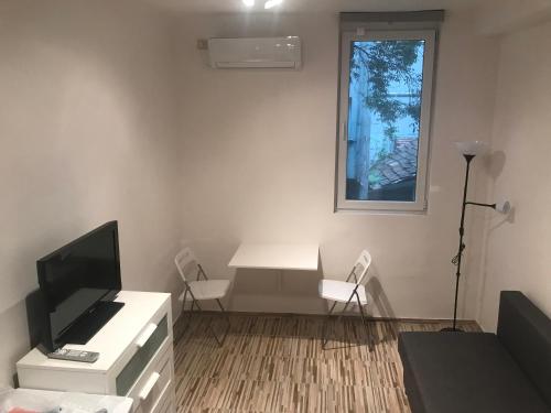 a living room with a tv and a desk and a window at Студио Чайка Бургас Център in Burgas City