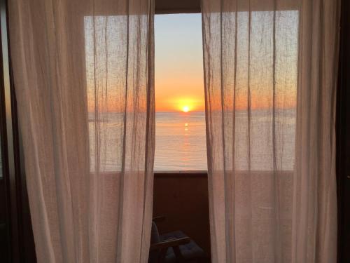 una ventana con cortinas y vistas a la puesta de sol. en La casa dell'Alba, en Marzamemi