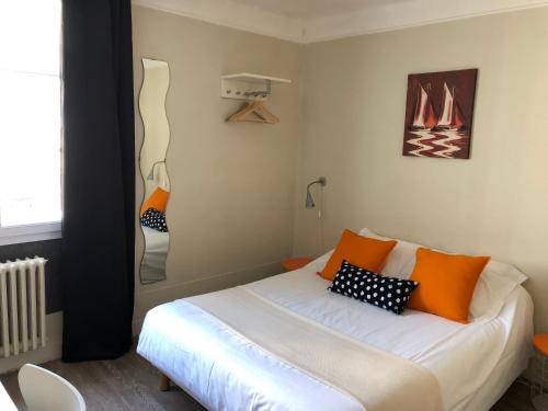 a bedroom with a bed with orange and black pillows at Le petit poucet in Saint Lo