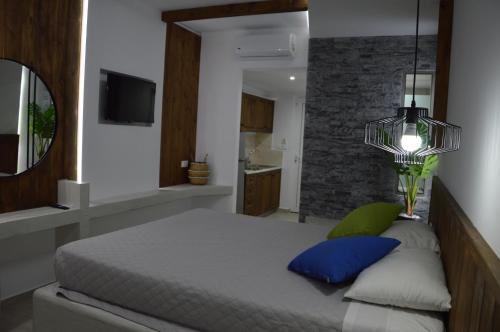 a bedroom with a bed with blue pillows and a mirror at Kostas Studios in Faliraki