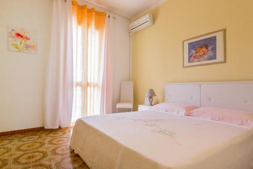 a bedroom with a white bed and a window at Casa La Formica in Noto